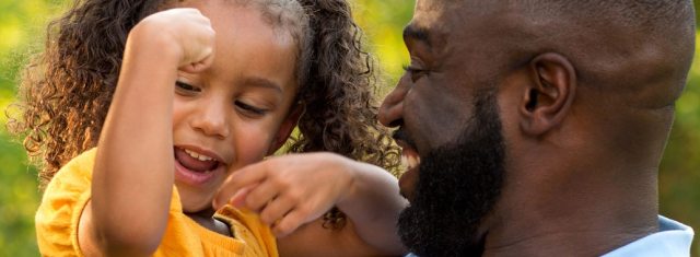 A smiling father holds his young smiling daughter