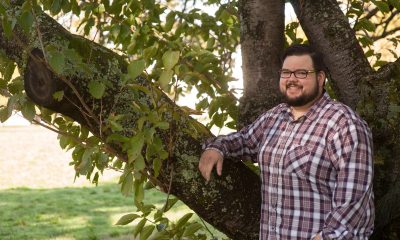 A man stands next to a tree while smiling