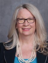 Photo of Eileen in front of a gray background