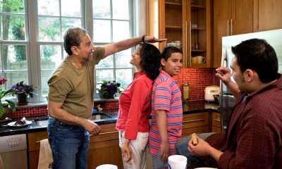 woman and teen boy stand back-to-back to compare heights
