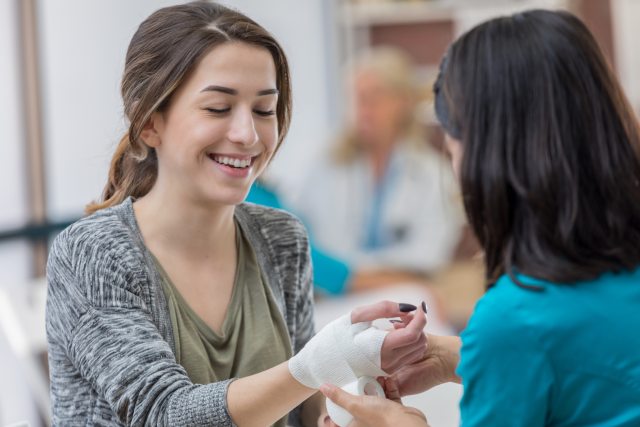 A Healthcare provider bandages the right arm of a smiling patient