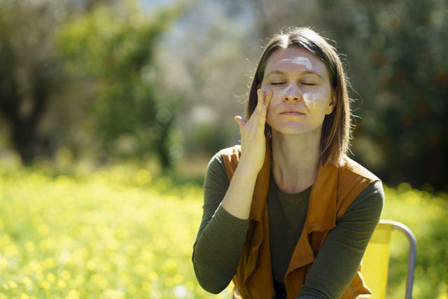 Woman putting face cream on her face.