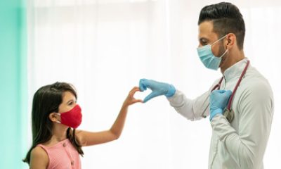 Young person in a mask makes heart sign with doctor in a mask