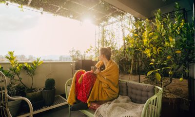 Woman sitting on patio with a yellow blanket and cup of tea.