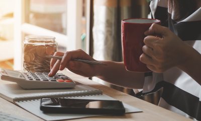Closeup of a person's fingers using calculator and holding a coffee cup