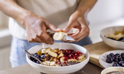 Woman cutting banana to add to a fruit bowl.