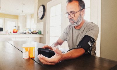 Man with beard measures blood pressure at kitchen table