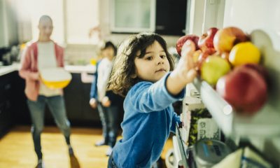 Young person reaches into fridge for an apple