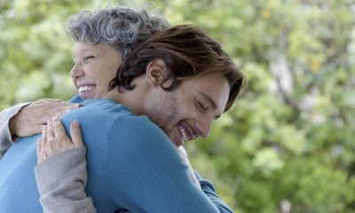 Older woman hugs a young adult man