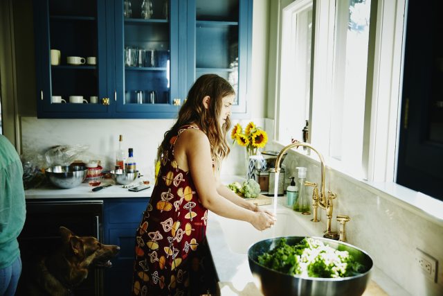 Woman washing her hands at the kitchen sink.