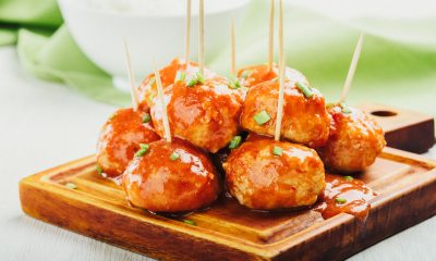 Buffalo chicken meatballs on a cutting board with toothpicks in them for easy eating.
