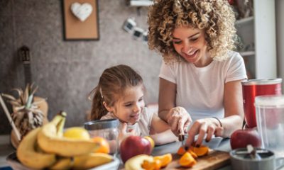 Young girl and young mother cut up fruit in their kitchen