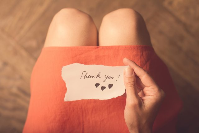 Close-up of Thank you note with drawn hearts, resting on a lap