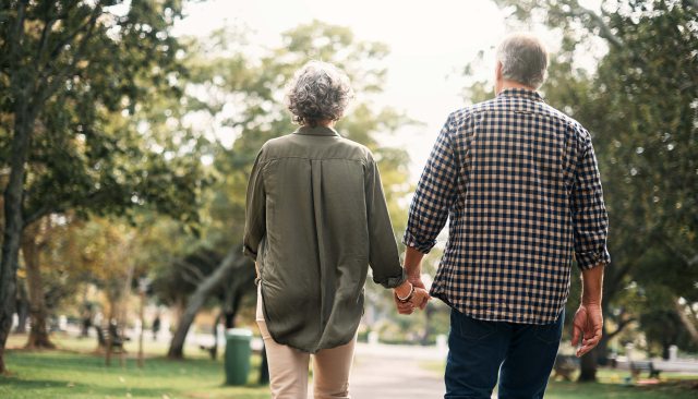 A hand-holding couple walks through a neighborhood lines with trees