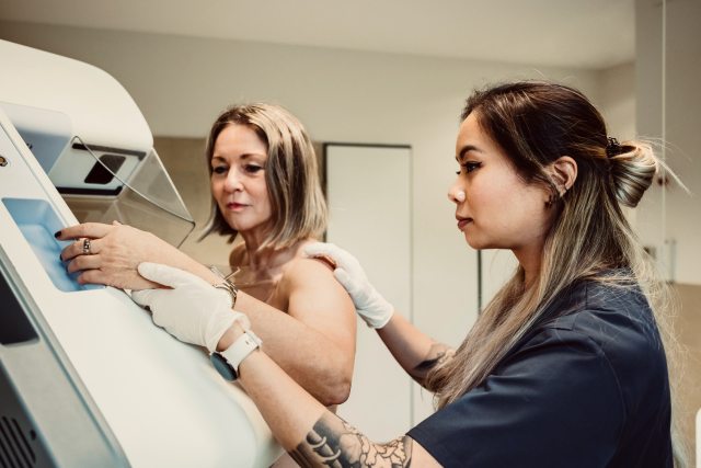 Patient getting mammogram with help from technician