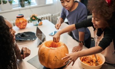 Woman and two children carve a pumpkin on the kitchen table
