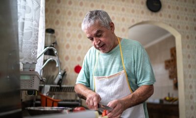 man with short white hair chops veggies in home kitchen