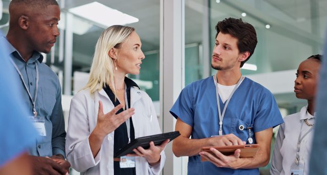 A group of healthcare providers discuss a medical chart in a clinical setting