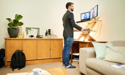 A man uses a standing desk for computer work